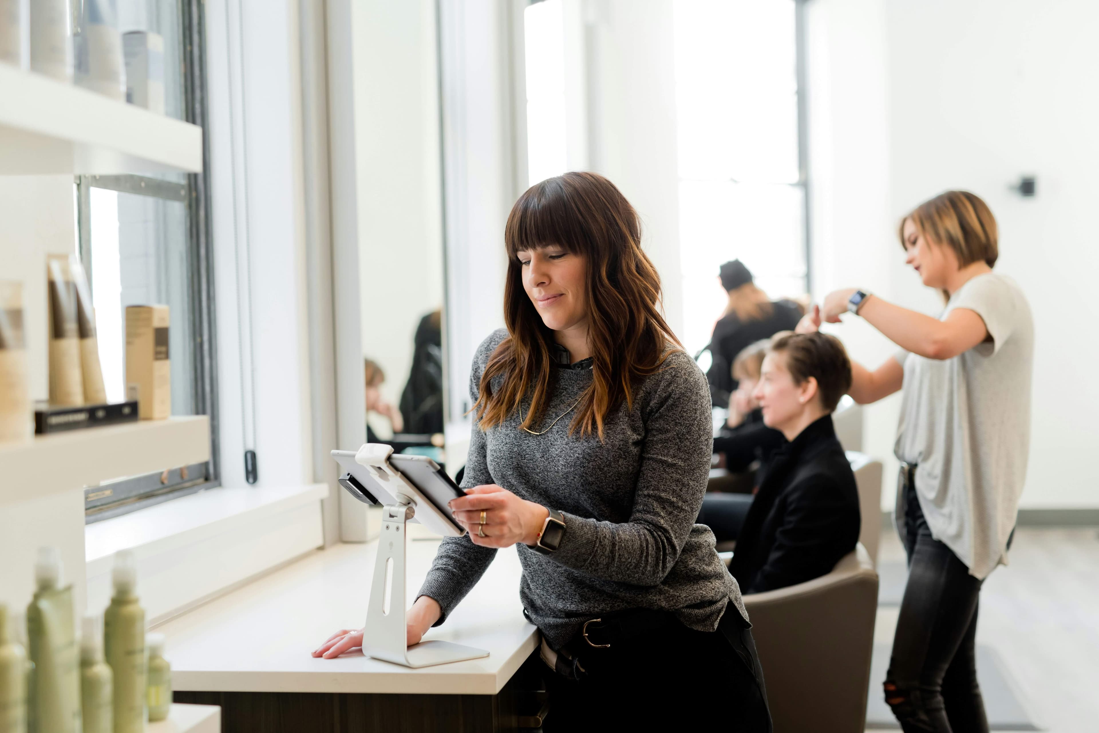 A small salon team at work, with the owner checking bookings on a tablet